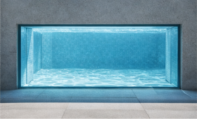 Front view of 4-sided vertical pool window recessed in concrete wall with blue water visible
