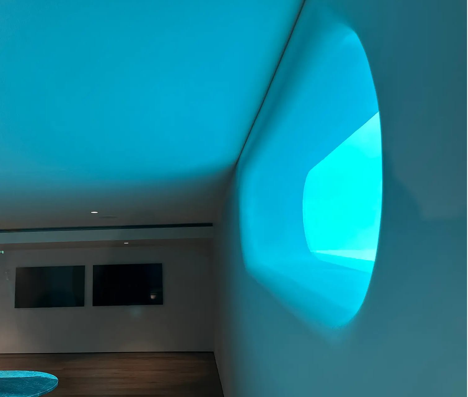Interior view of Hazler Pools Brighton acrylic pool window casting turquoise light across viewing room