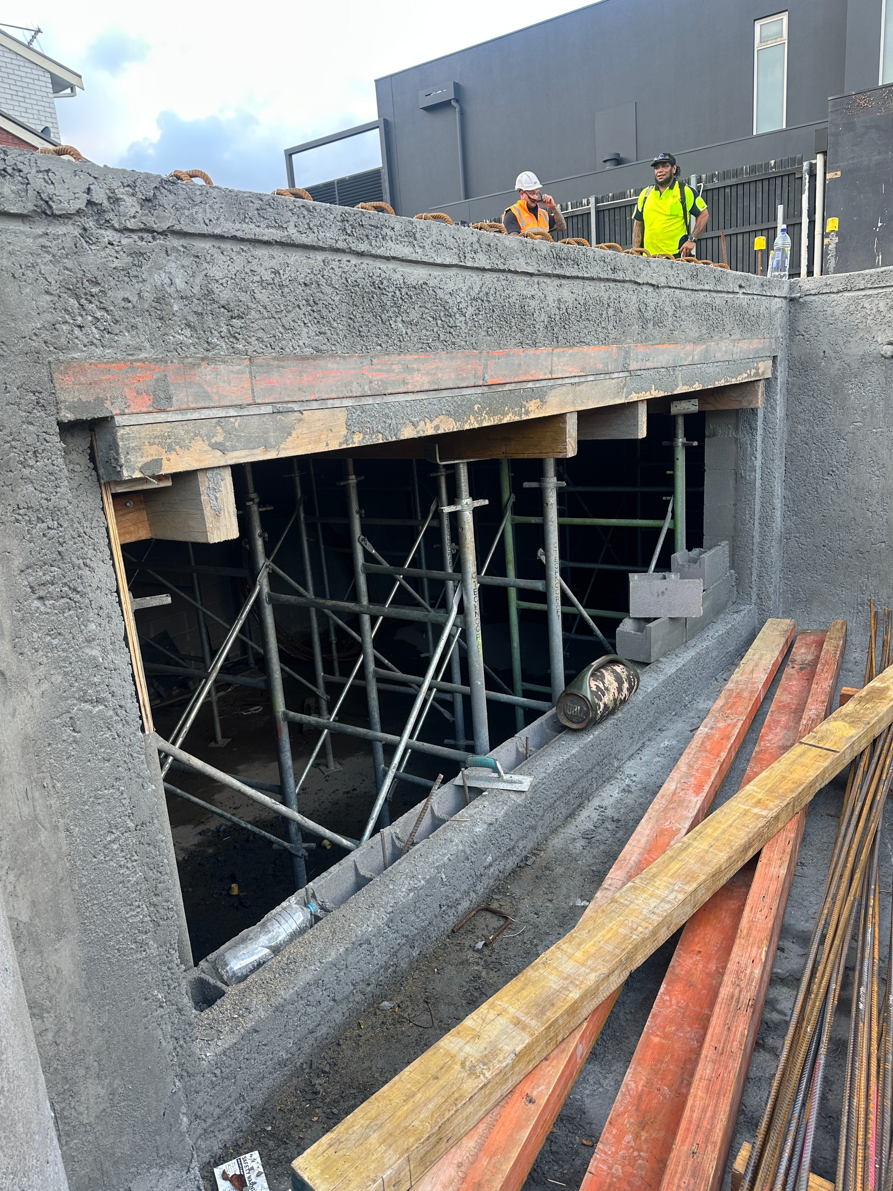 Construction workers overseeing the Brighton Residence pool panel installation with scaffolding and concrete formwork