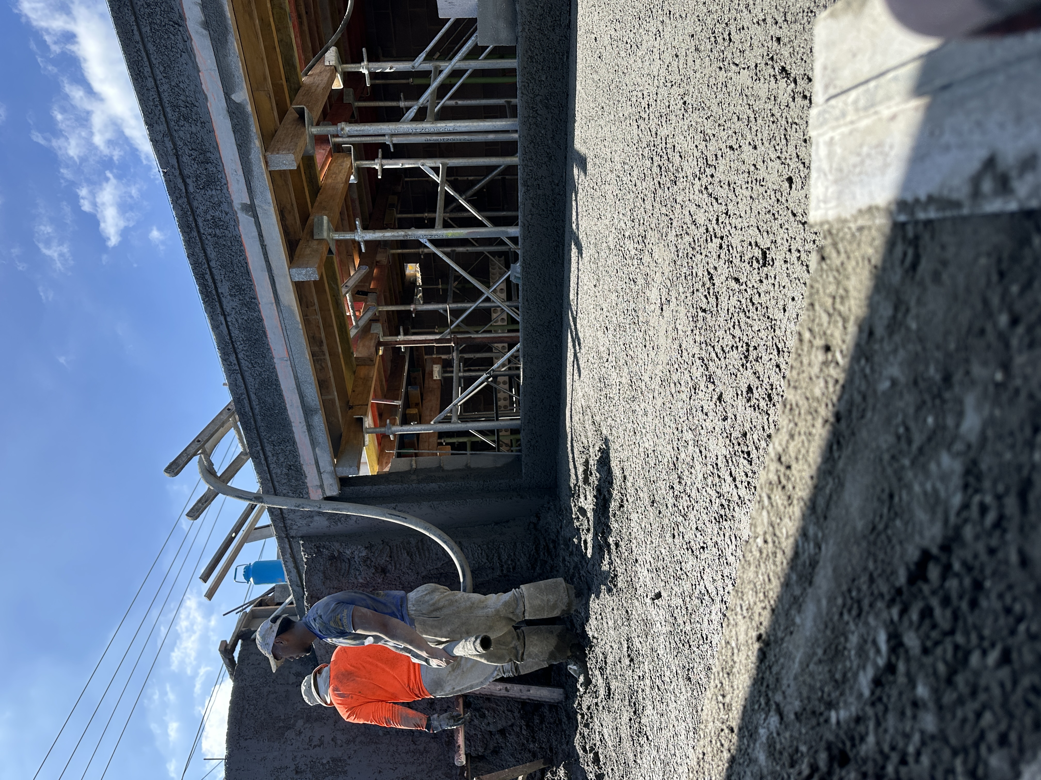 Concrete pouring operation with workers and scaffolding framework